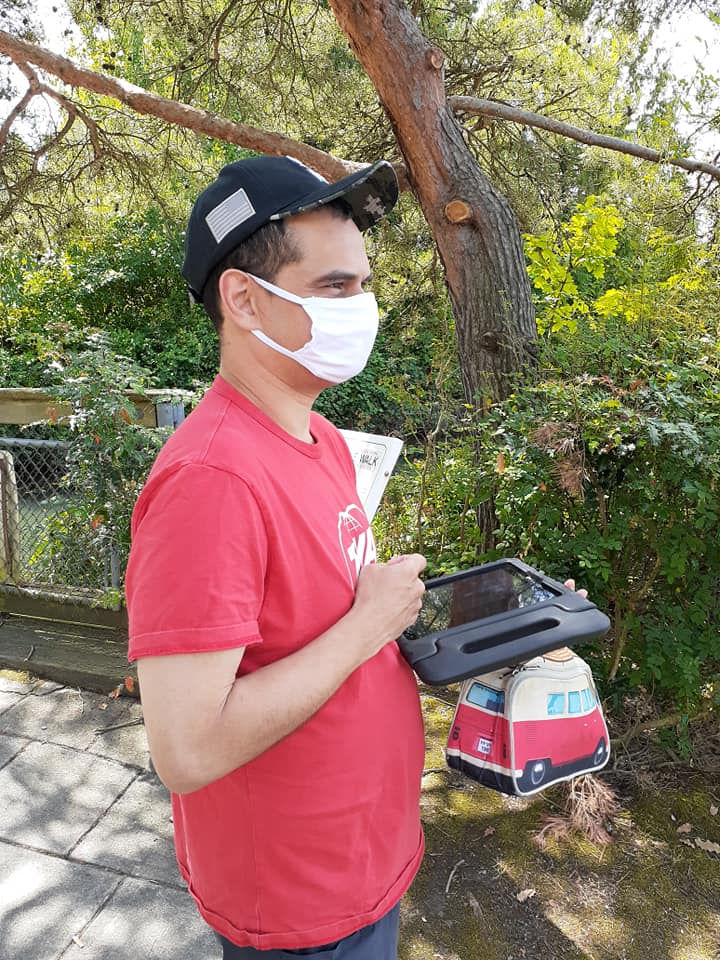 A man has his ipad out, while walking in a park